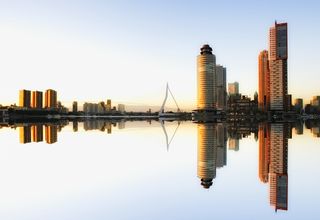 Captivating view of Rotterdam skyline reflecting in water at dusk, showcasing modern architecture.