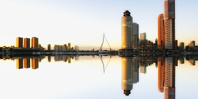 Captivating view of Rotterdam skyline reflecting in water at dusk, showcasing modern architecture.