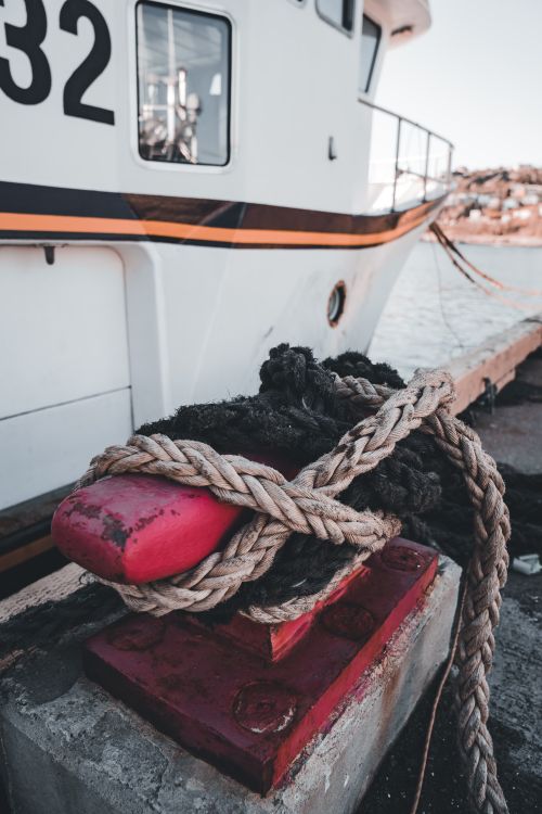Free Detailed view of a boat docked with sturdy ropes at a harbor on a clear day. Stock Photo