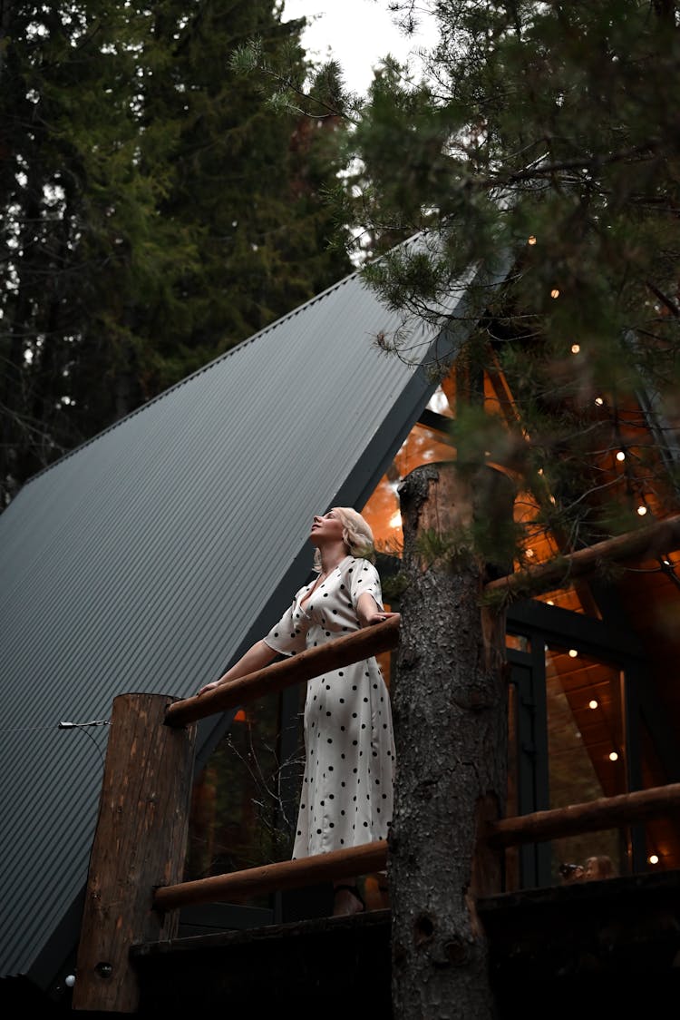 Woman Posing On Terrace Of House Among Trees