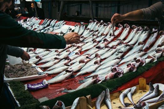 Vibrant fish market scene with fresh fish and people interacting at the seafood stall.