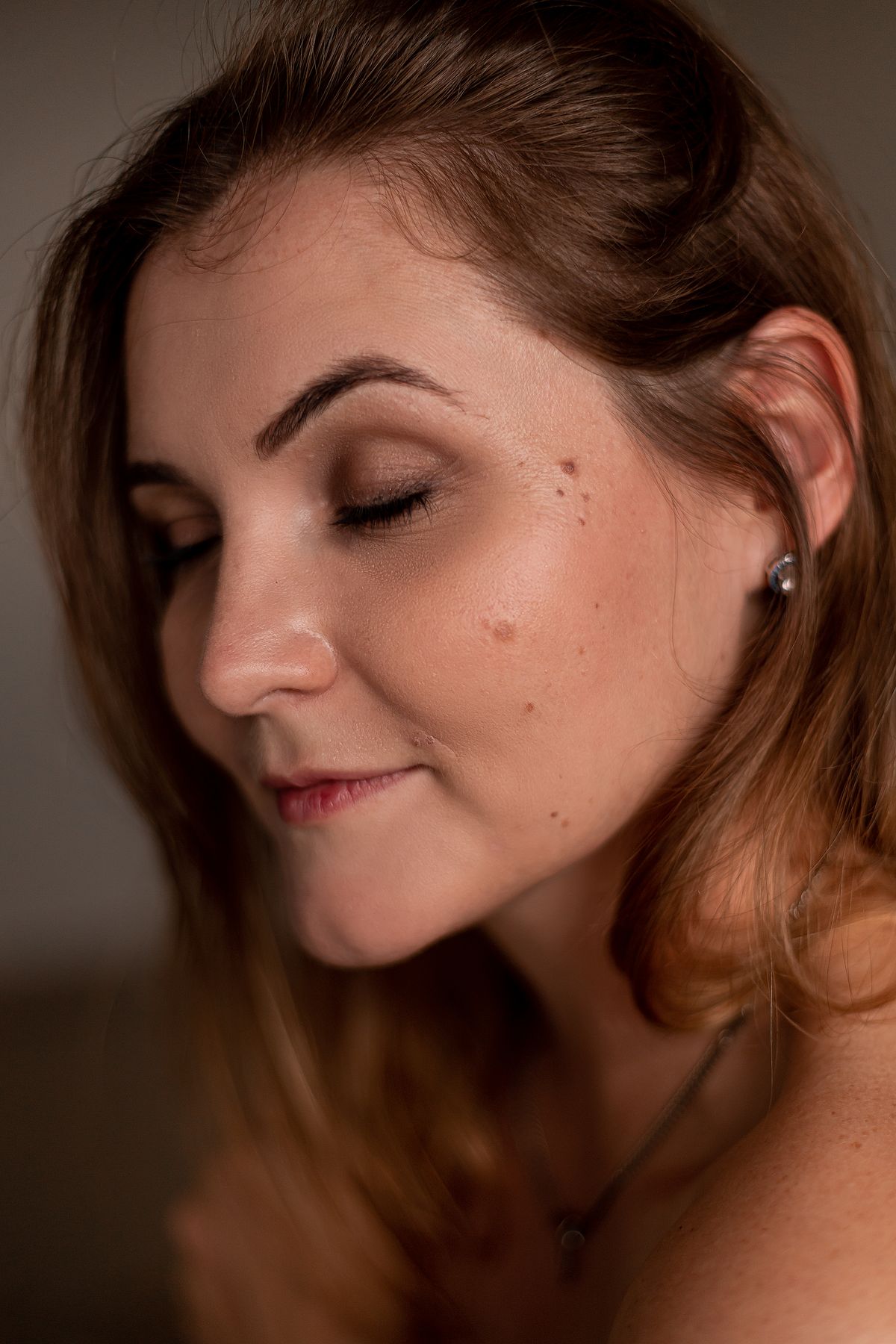 Retrato en luz cálida de una mujer adulta con la piel sin retocar: pecas, lunares y textura a la vista