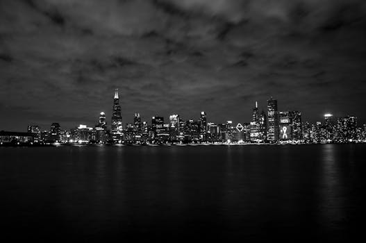 Dramatic black and white photo of Chicago skyline at night across the water.
