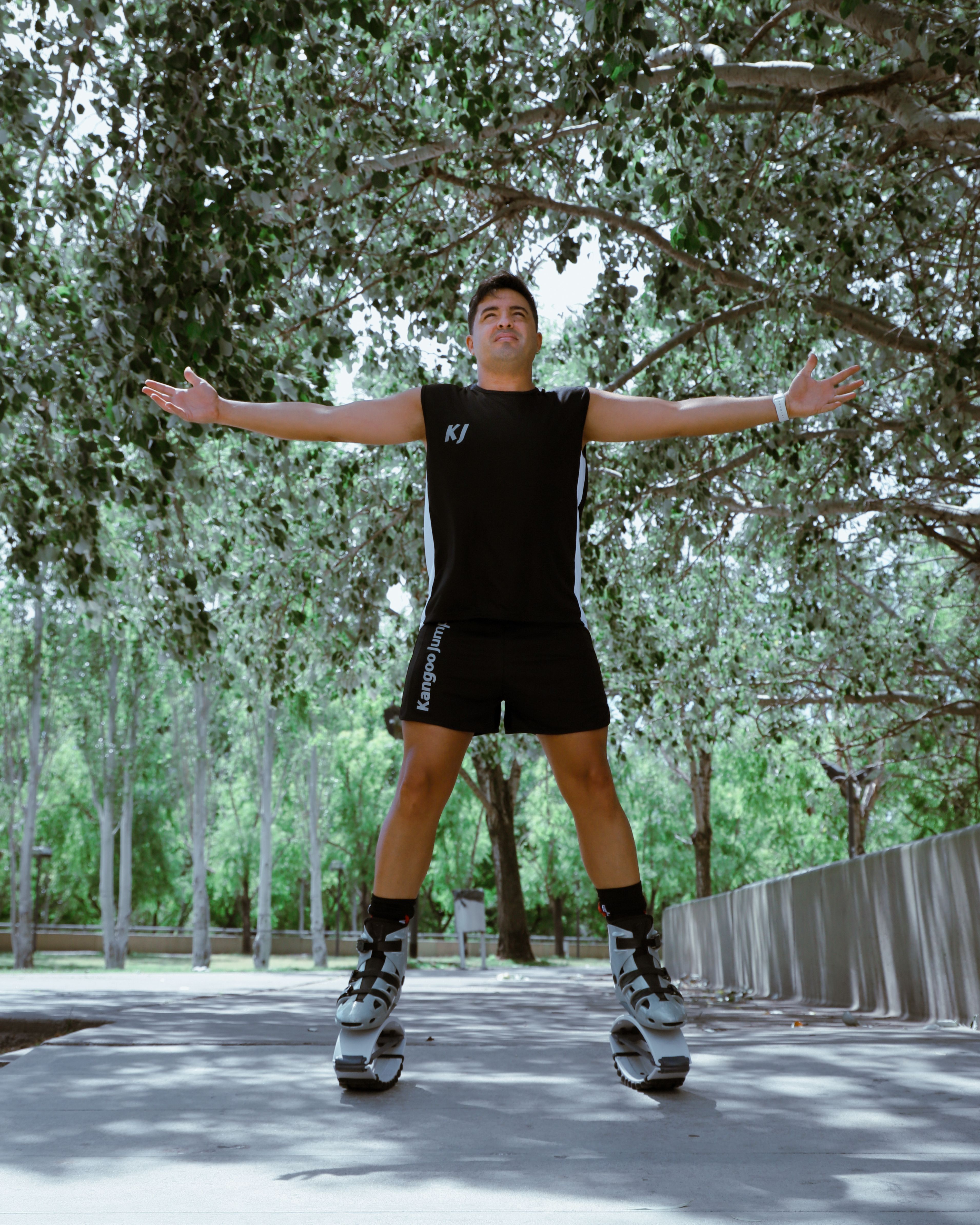 Man in rebound jumping boots stretching his arms outdoors