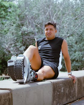 Man seated on a ledge outdoors, wearing kangaroo boots for exercise and relaxation.