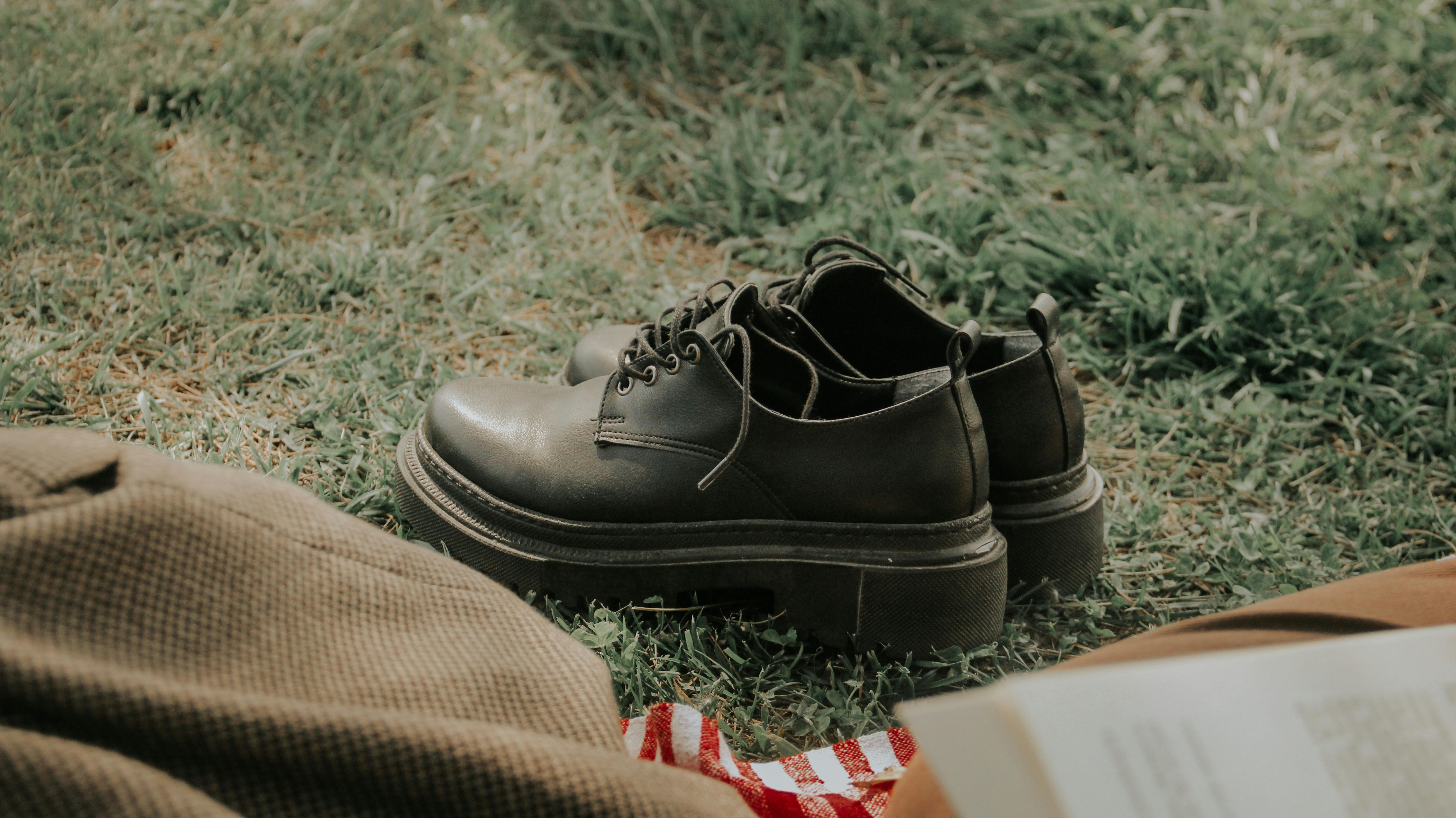 A pair of vintage leather shoes resting on green grass, captured in a rural outdoor setting.