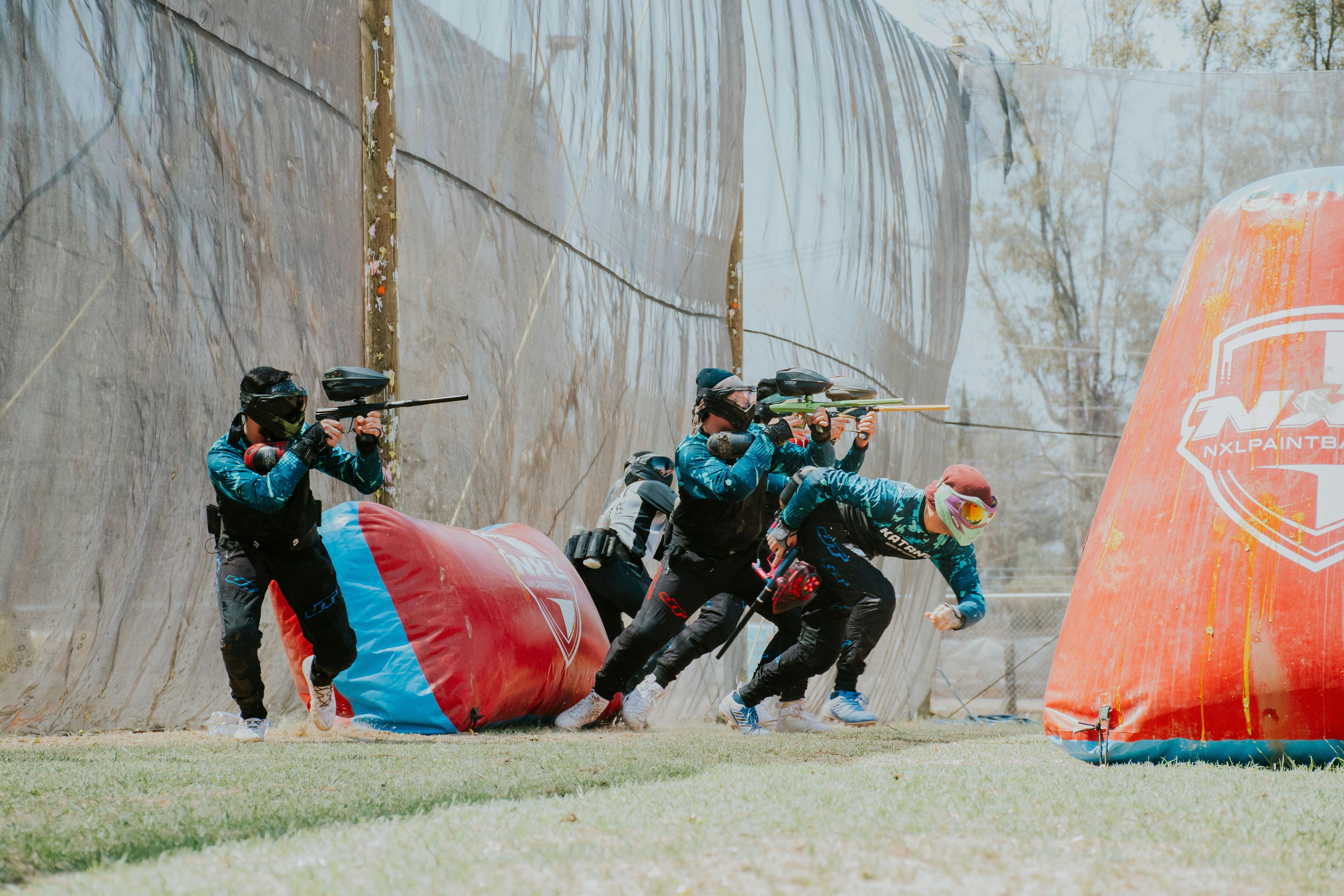 Ein Team von Spielern nimmt an einem spannenden Paintballspiel im Freien teil, bei dem Teamwork und Strategie im Vordergrund stehen. Prescription Goggle Inserts - Team of players engaged in an energetic outdoor paintball game, showcasing teamwork and strategy.