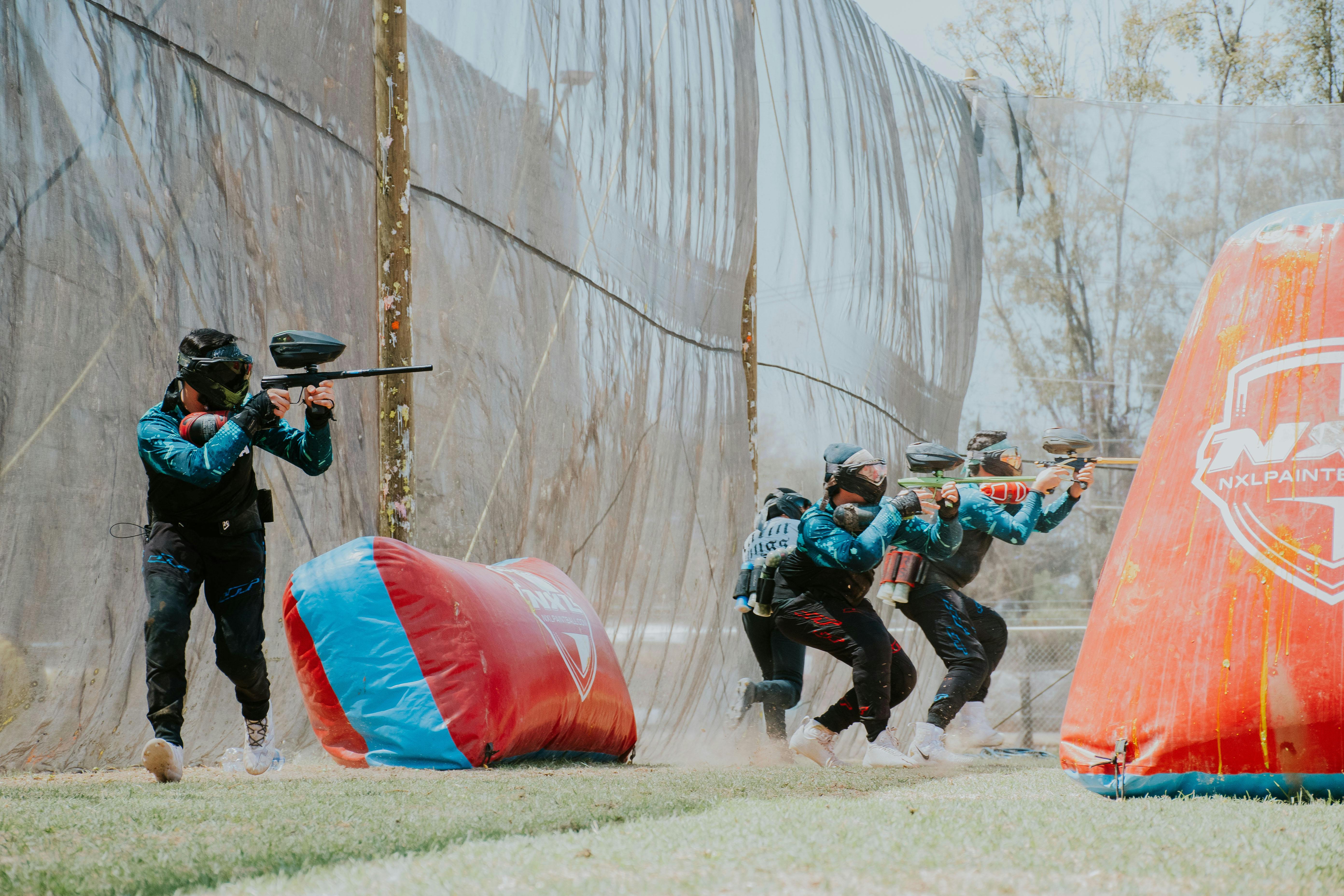 Four players engaged in an intense paintball match at an outdoor field. Prescription Goggle Inserts - Four players engaged in an intense paintball match at an outdoor field.