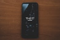 一部智能手机显示着时间，放在木制表面上，展现了现代技术