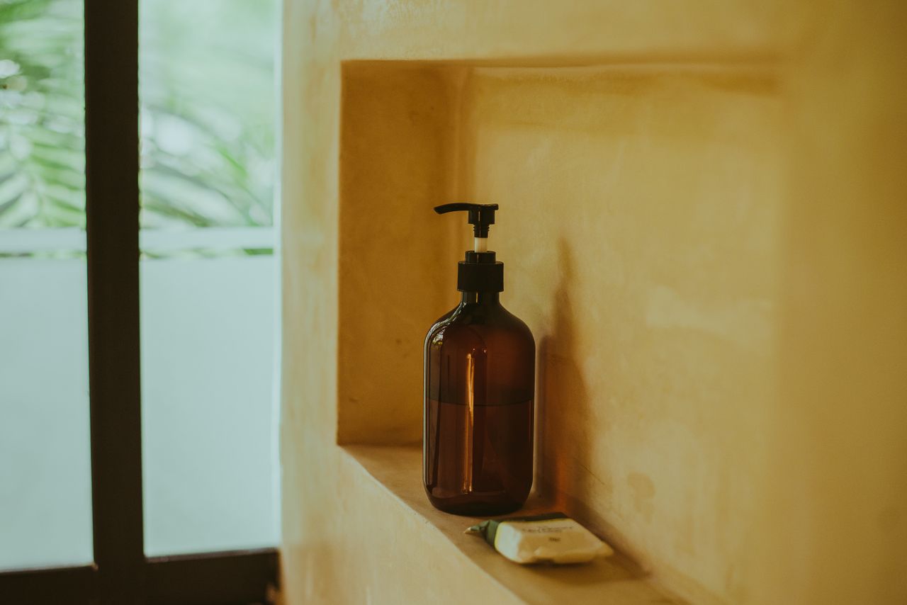 Amber pump bottle and a fresh bar of soap in a shower niche