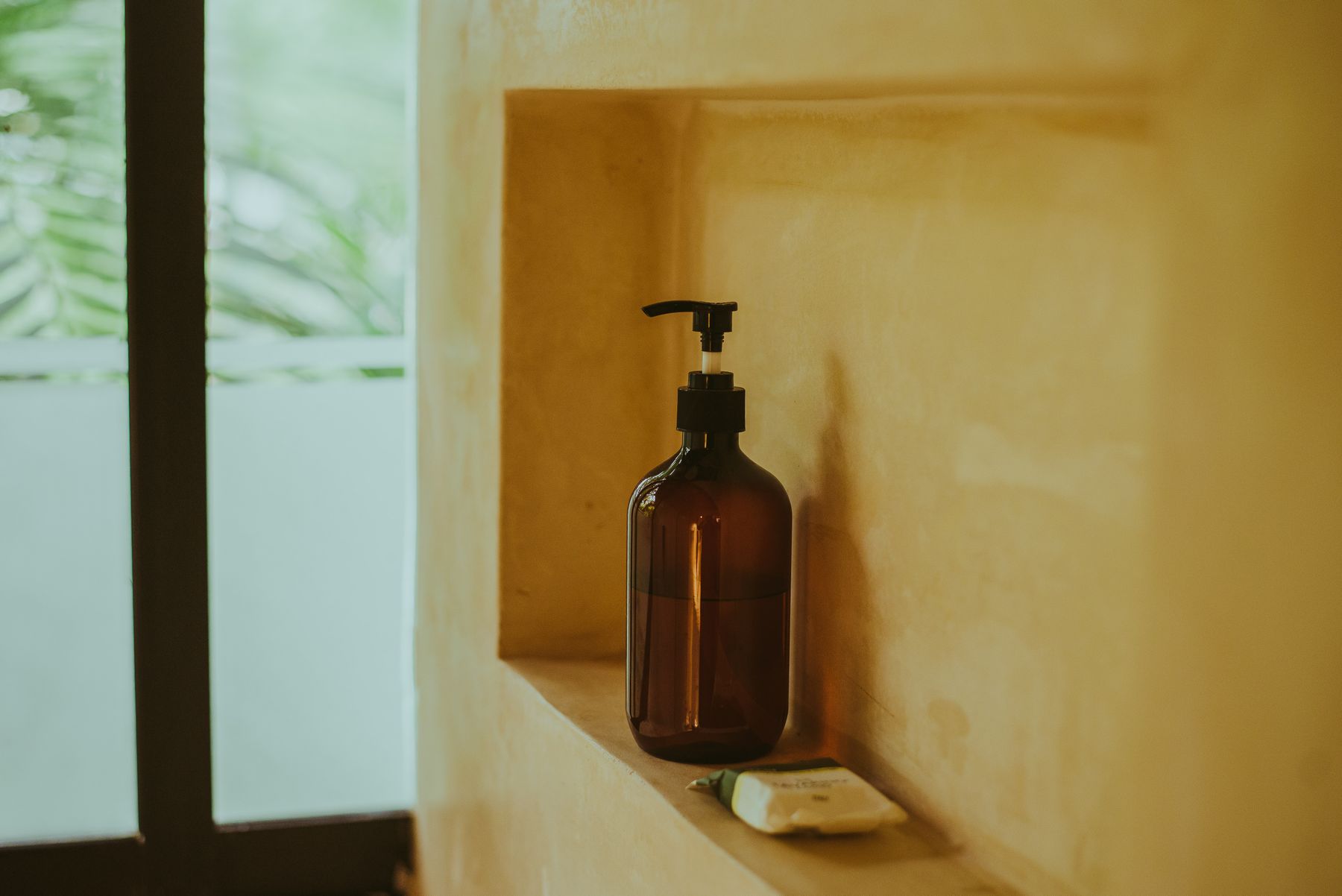 An amber bottle and a soap bar resting on a minimalist bathroom shelf