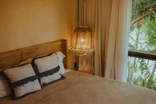 Neatly Made Bed and a Hanging Lamp in a Hotel Room 