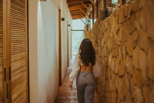 Back View of a Young Brunette Walking in a Hallway 