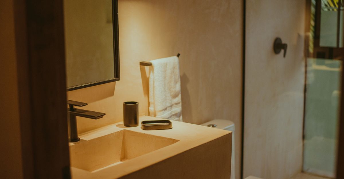 Contemporary bathroom interior with minimalist design and soft lighting, featuring mirror and sink.