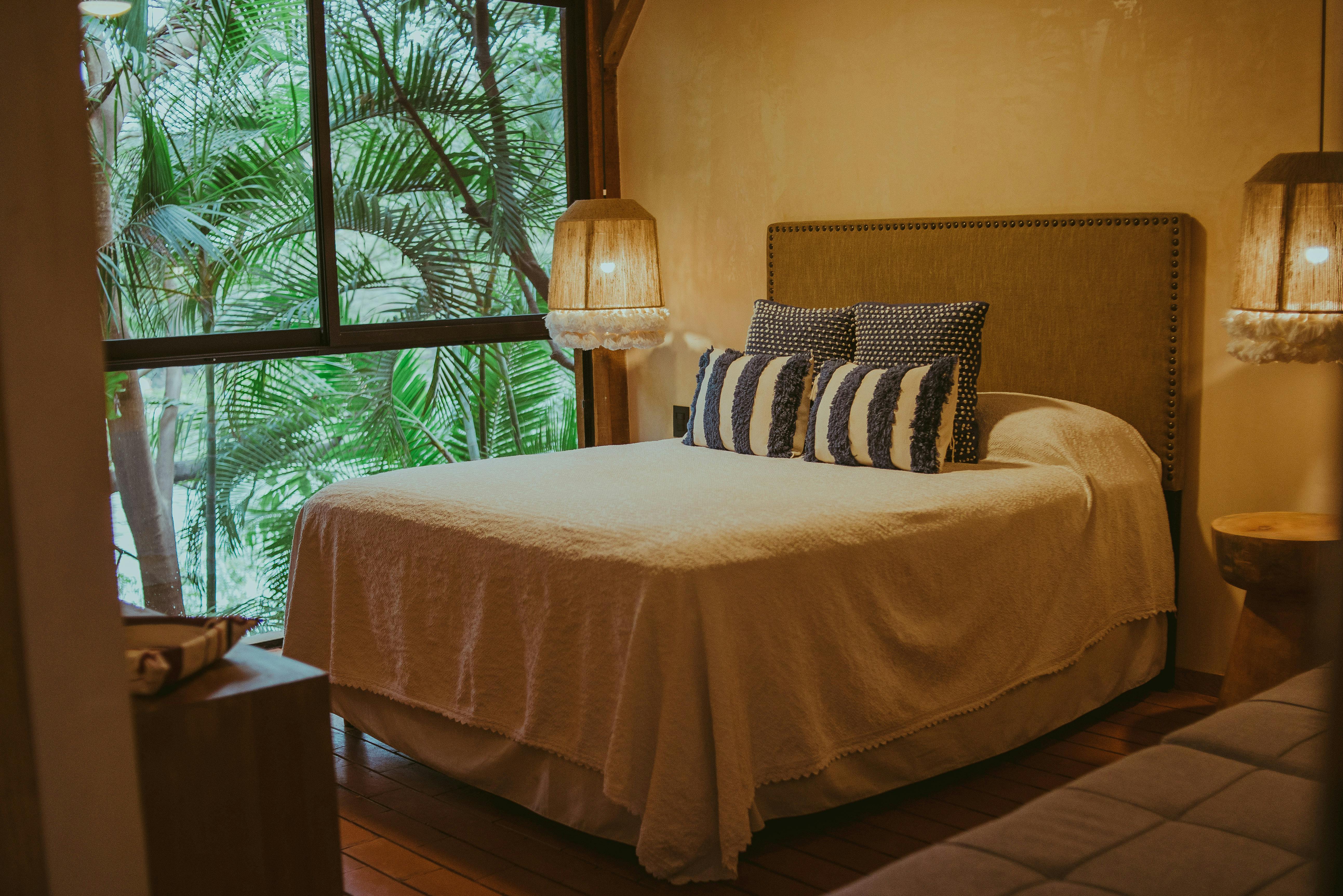 Warm and inviting bedroom with a view of lush greenery, featuring a comfortable bed and stylish decor.