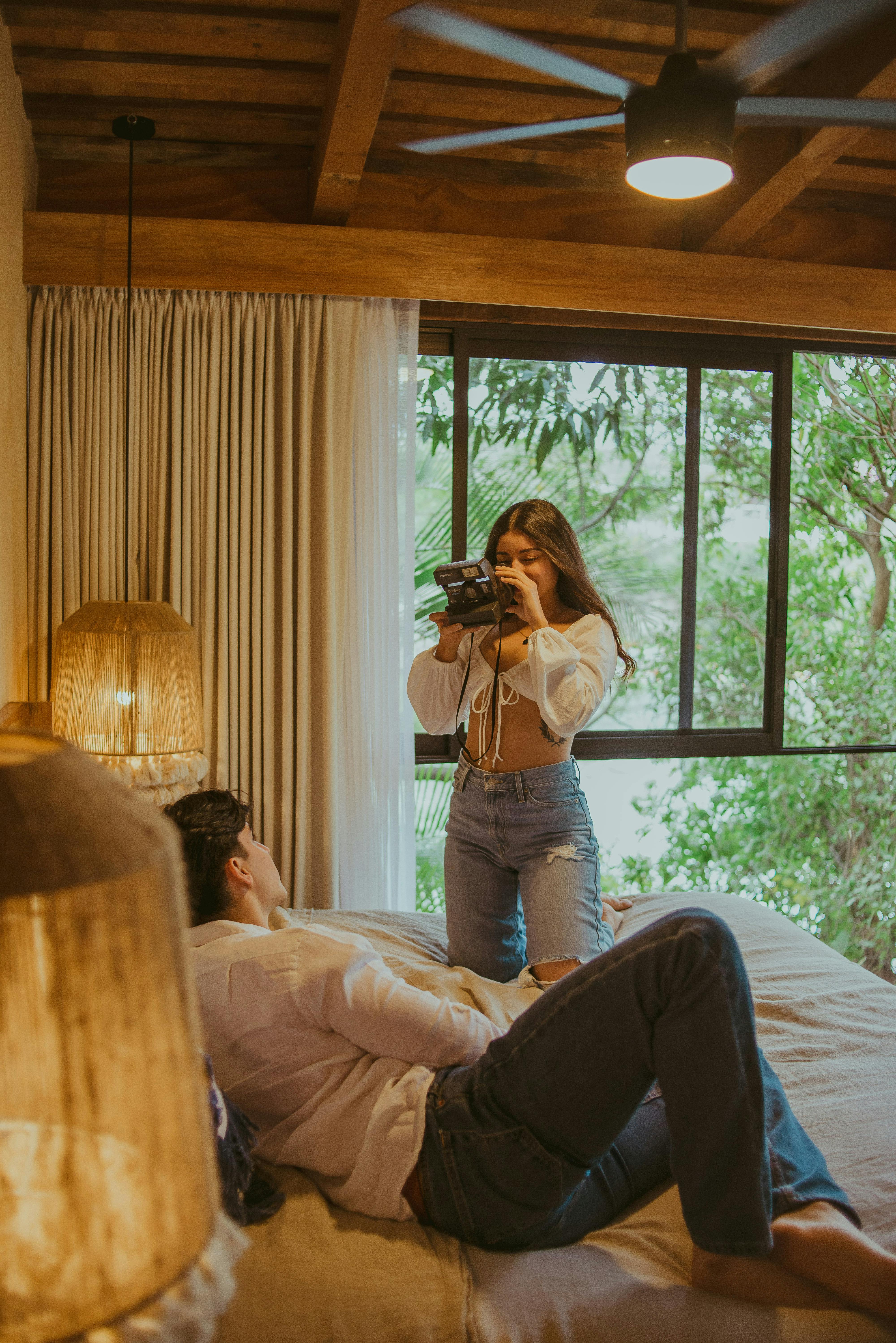 A couple capturing moments in a rustic bedroom with warm lighting and natural views.