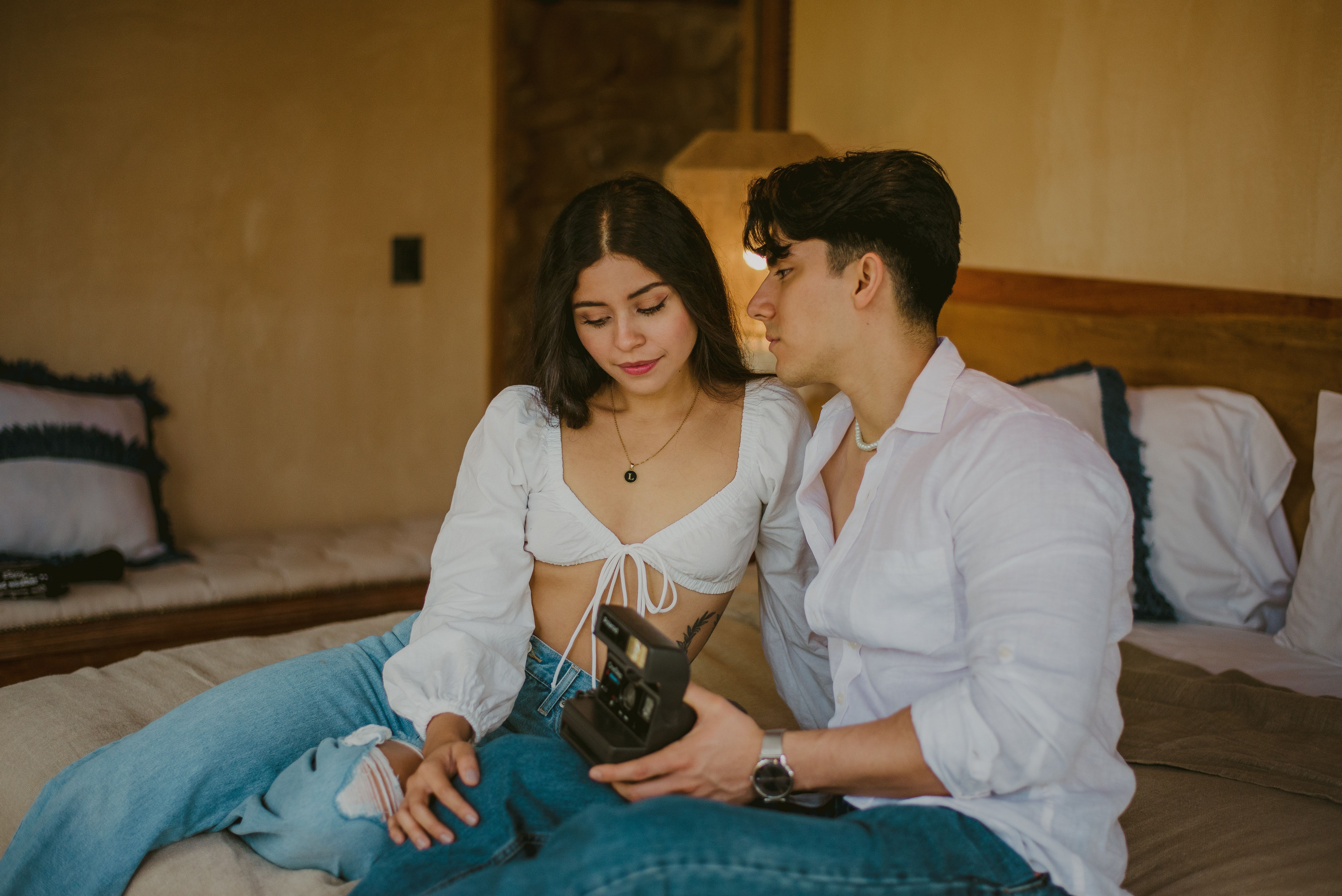 A young couple lovingly sits on a bed in a cozy and relaxed atmosphere.
