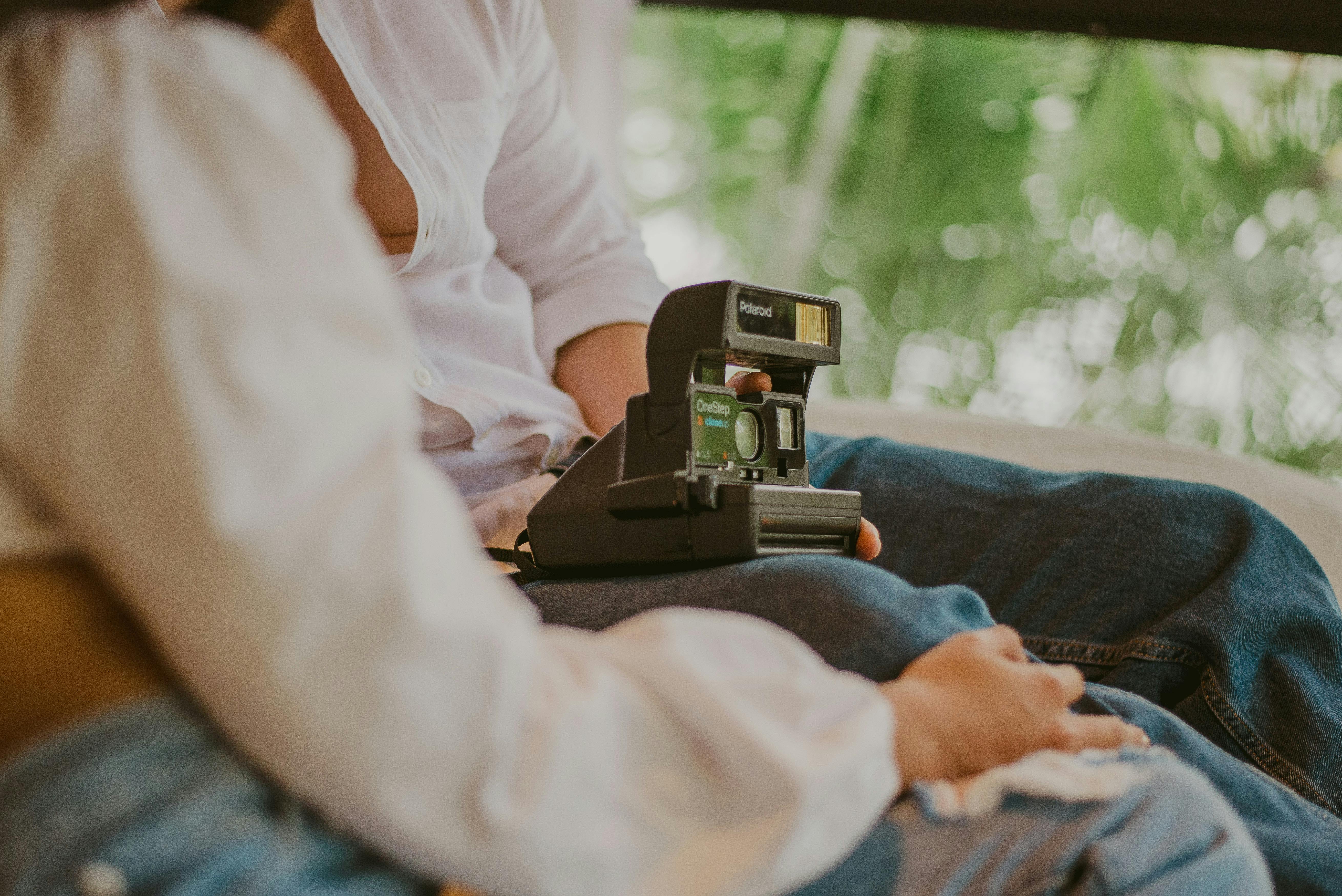 Close-up of a couple sitting together holding a vintage Polaroid camera.