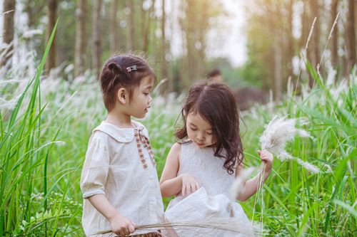 Free Two young girls enjoy a sunny day in a lush green field, embodying innocence and joy. Stock Photo
