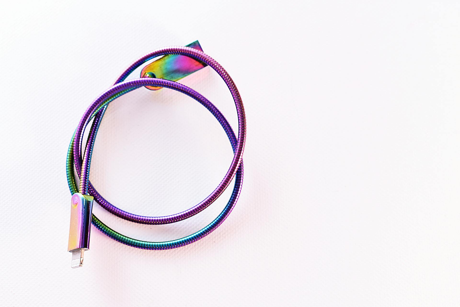 A vibrant, rainbow-colored USB cable coiled on a bright white surface.