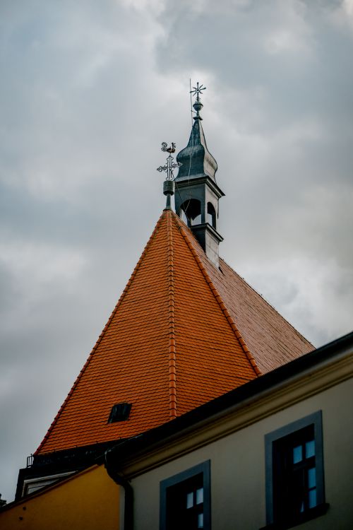 Free A tower with a red-tiled roof rises against a cloudy sky, featuring traditional architecture. Stock Photo