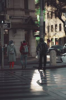 People crossing a street in a city setting with urban architecture and natural light.
