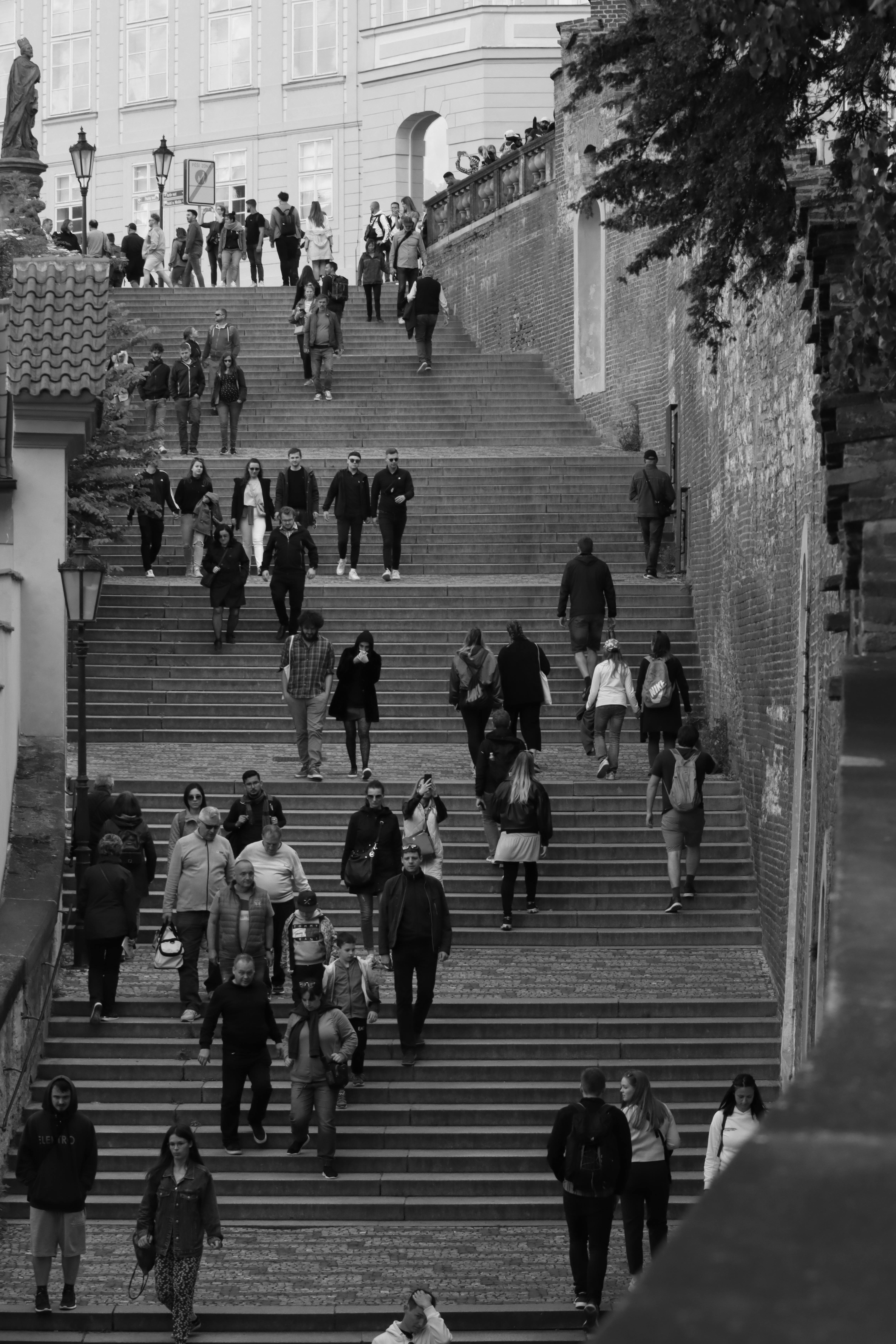 Black and white photo of people walking on historic outdoor stairs in Prague, Czech Republic.