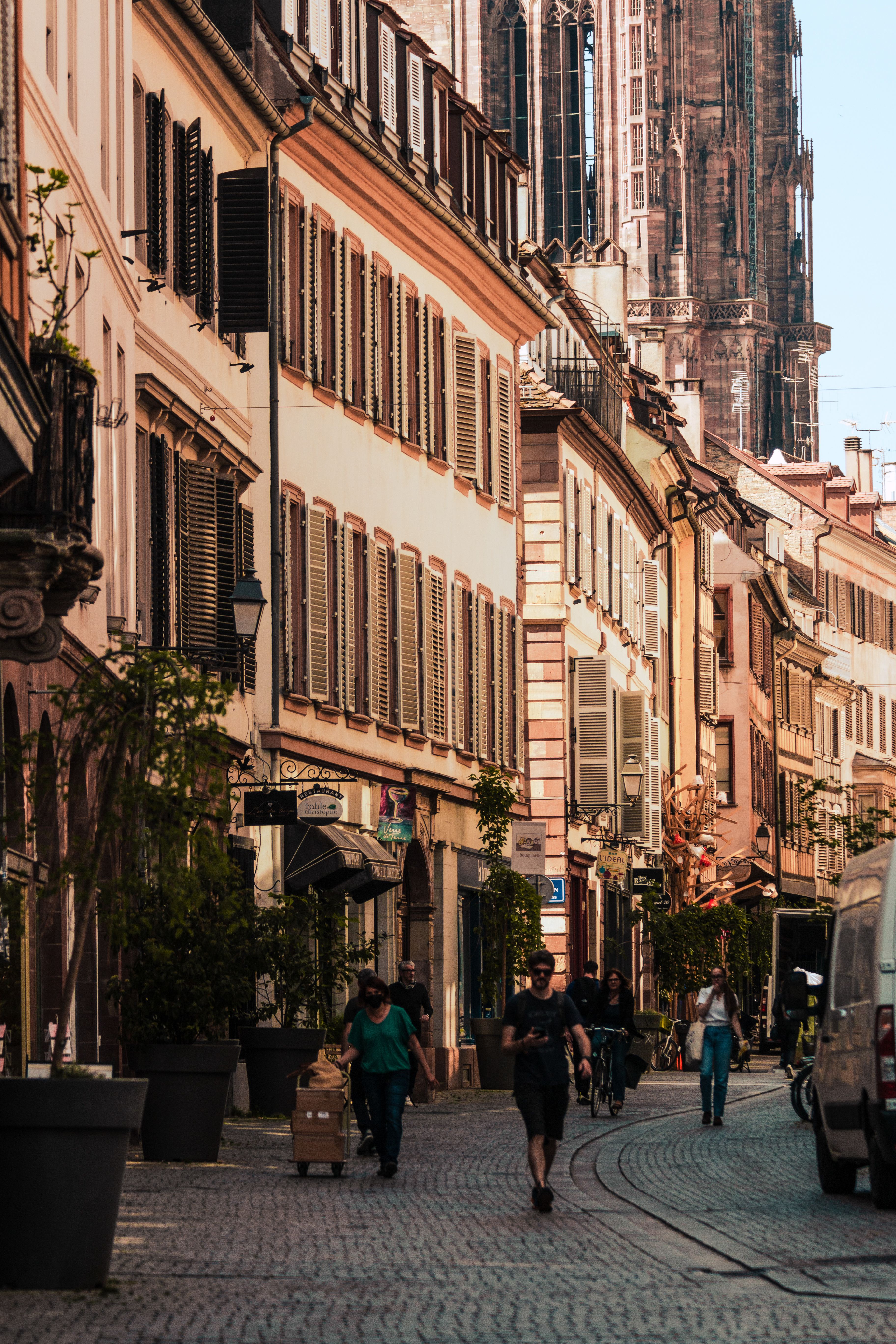 Rue pavée de Strasbourg bordée d'immeubles anciens à plusieurs étages, en pleine activité.