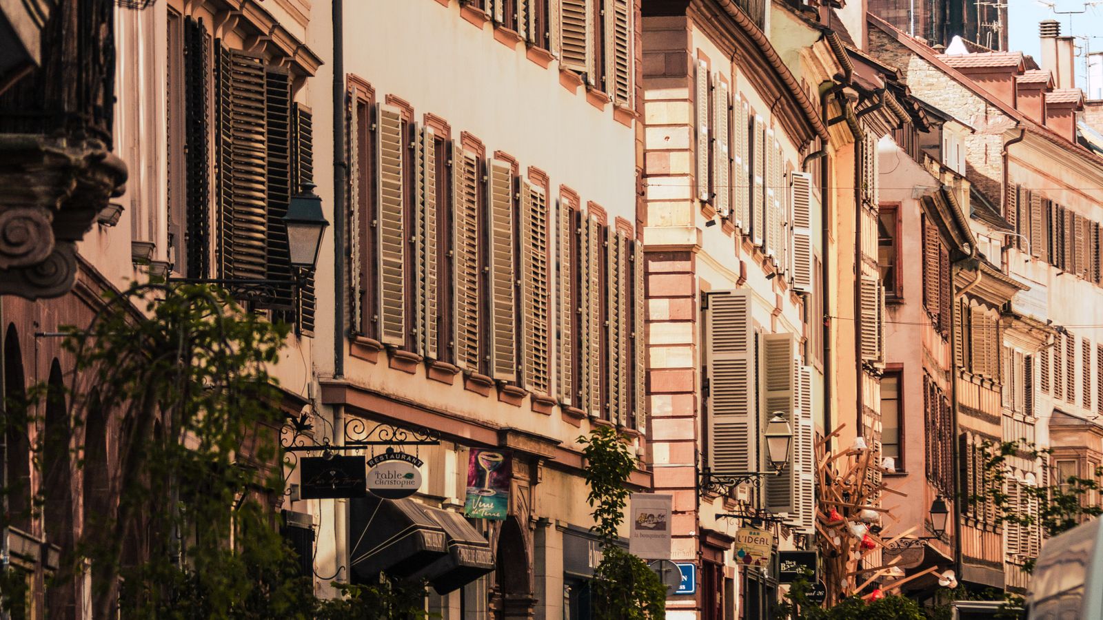 Rue pavée de Strasbourg bordée d'immeubles anciens à plusieurs étages, en pleine activité.