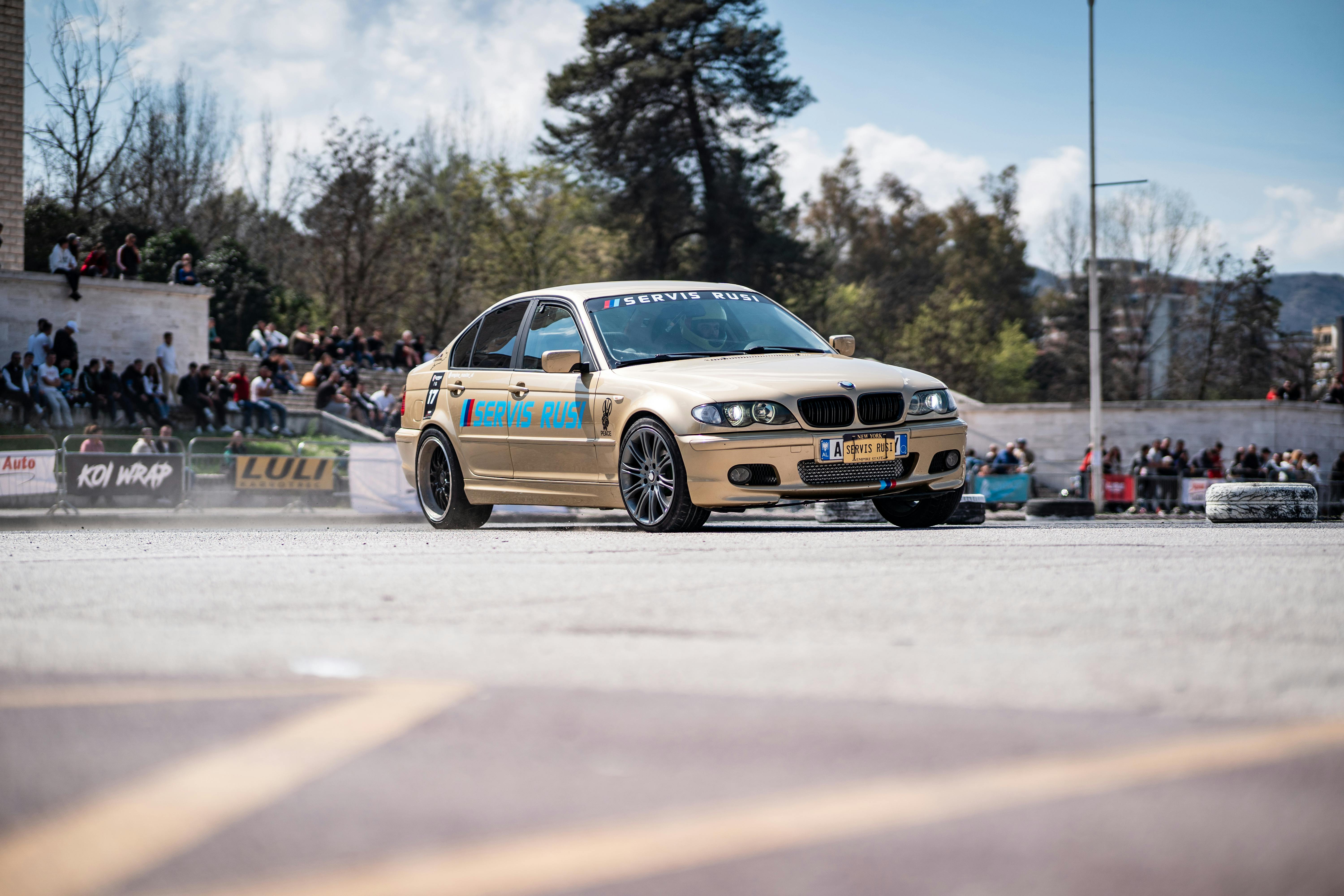 A BMW E46 car performing a drift on an outing during a motorsport event with an audience watching.