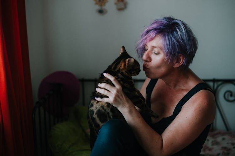 A Woman With Purple Hair Holding A Cat