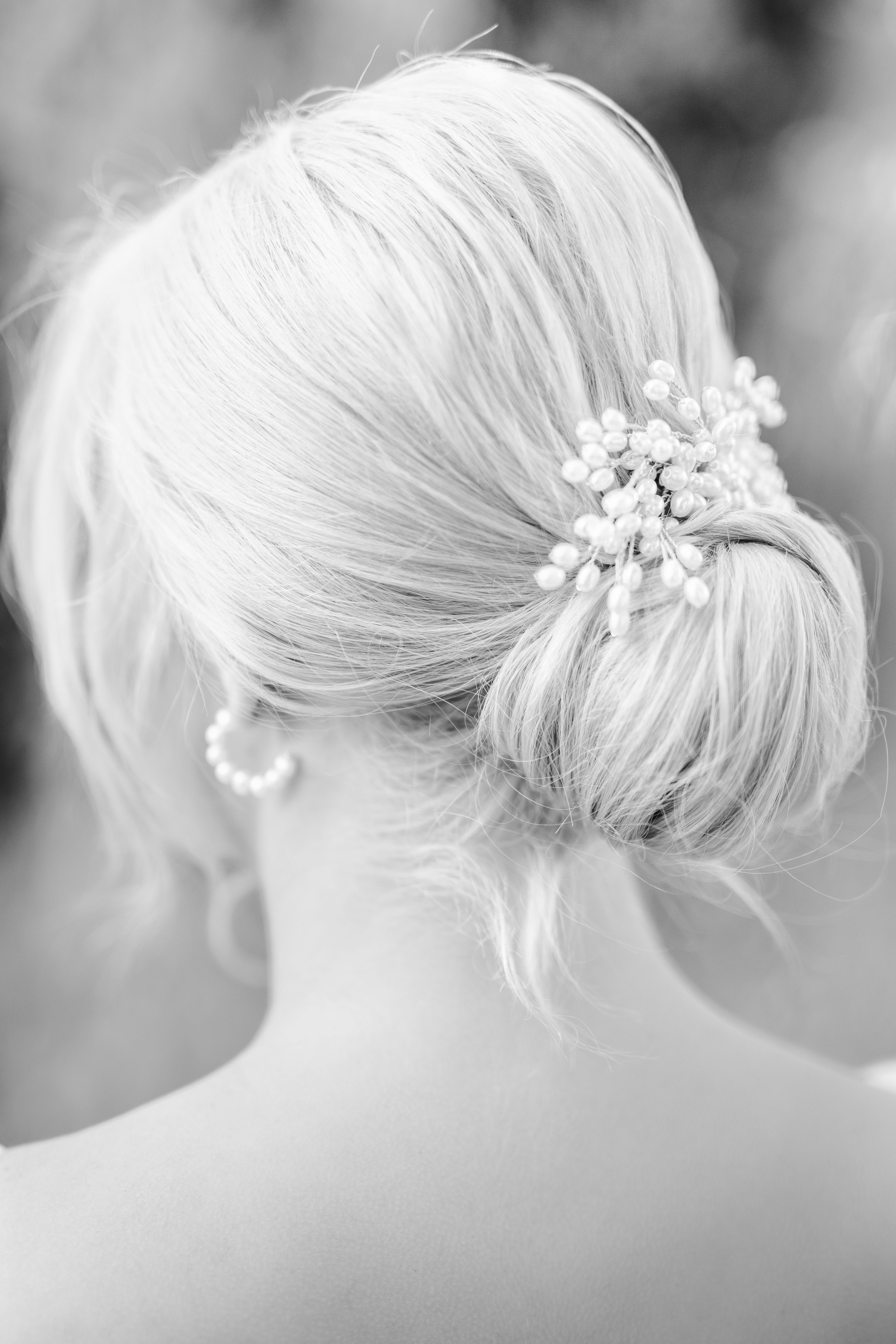 Back view of an elegant bridal hairstyle adorned with floral pearls in black and white tone.