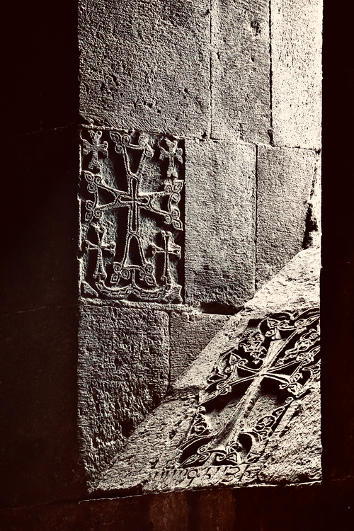 Free Detailed image of an engraved stone cross in a historic monastery wall contrasting with light and shadow. Stock Photo