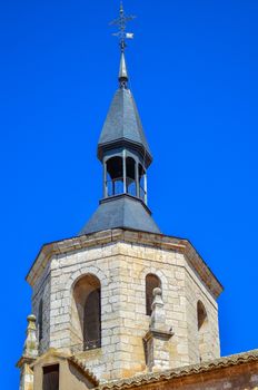 Stunning vertical shot of a traditional church tower in Daimiel, highlighting its architectural details against a clear blue sky.
