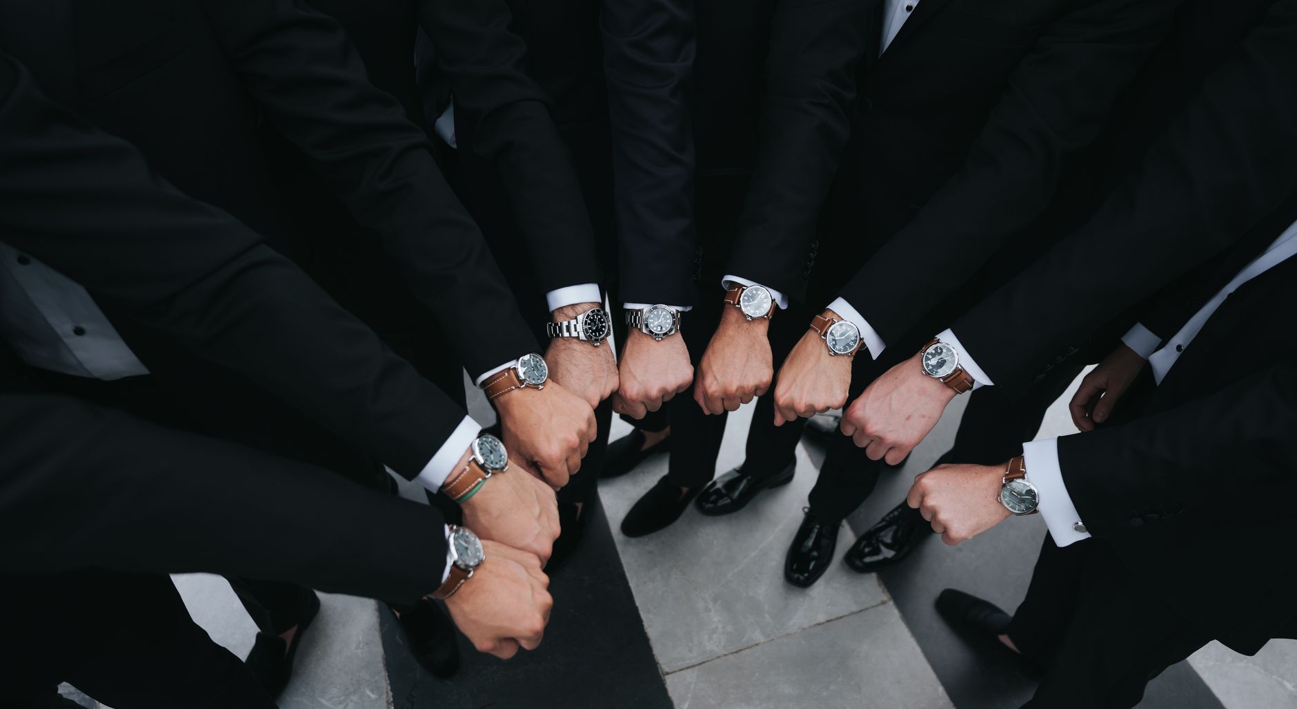 Group of executives showing luxury wristwatches in unity gesture.