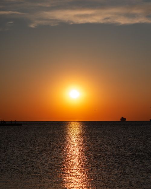 Free A tranquil sunset casting warm tones over the calm sea, creating a peaceful and scenic view. Stock Photo