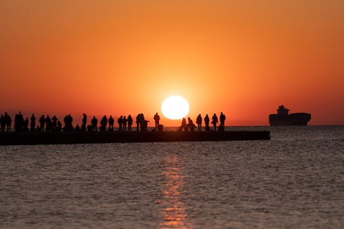 People on Pier on Sea Shore at Sunset