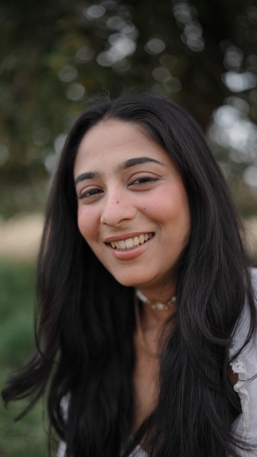 Free A portrait of a smiling woman with long black hair in an outdoor setting. Stock Photo