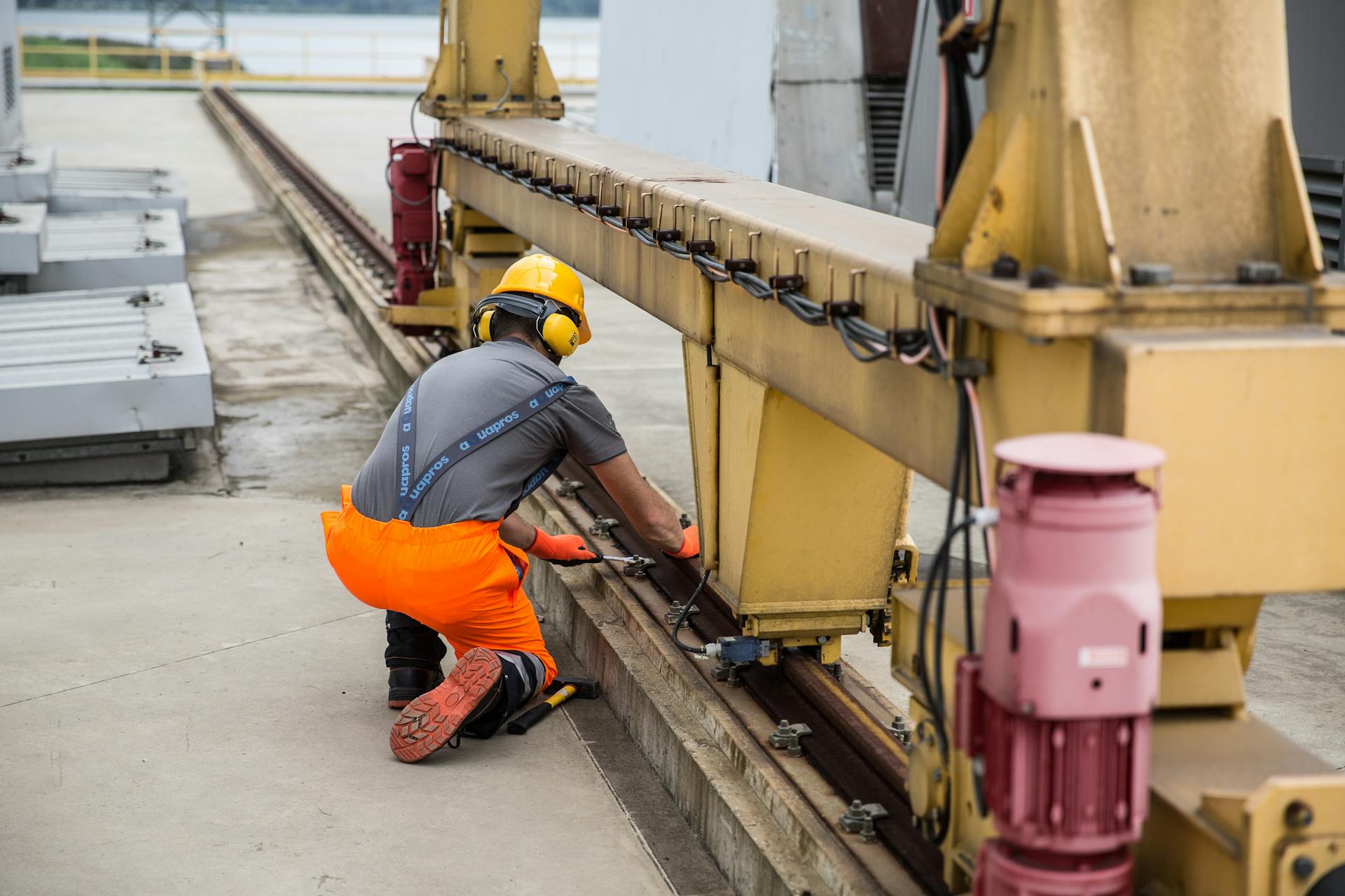 Worker in safety gear inspecting machinery on an outdoor industrial site.