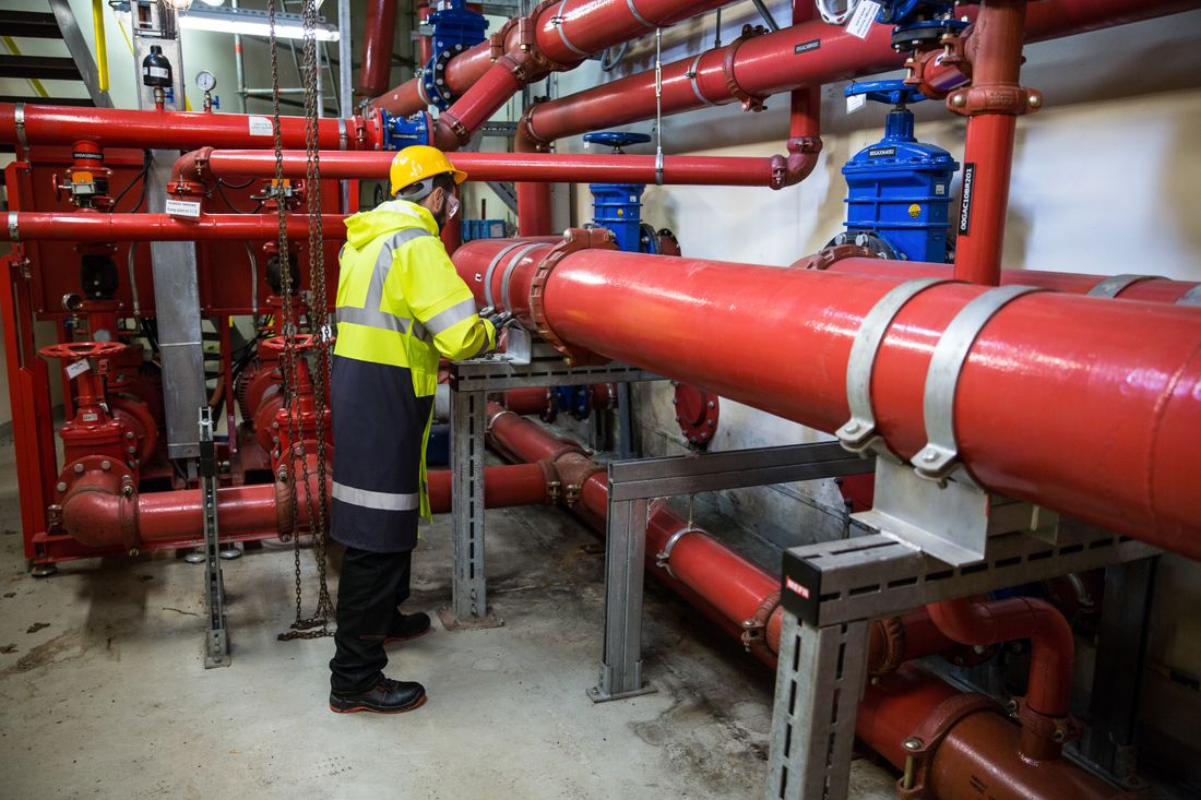 Plumber urgently working on exposed piping with flashlight during an emergency repair