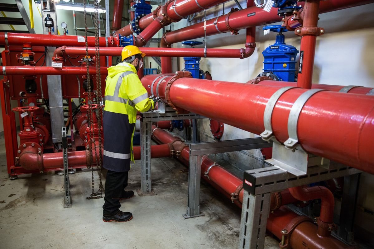 Engineer inspecting pipes and valves in a building mechanical room