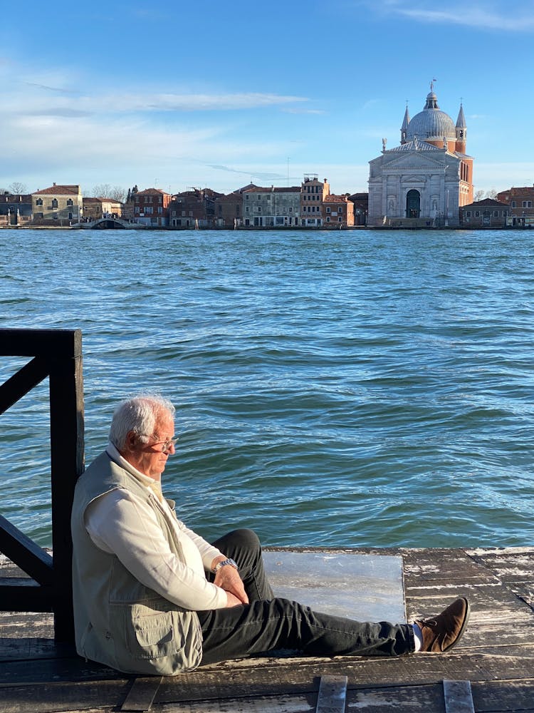 Waterfront With A Church, And A Senior Man Sitting By A Canal 