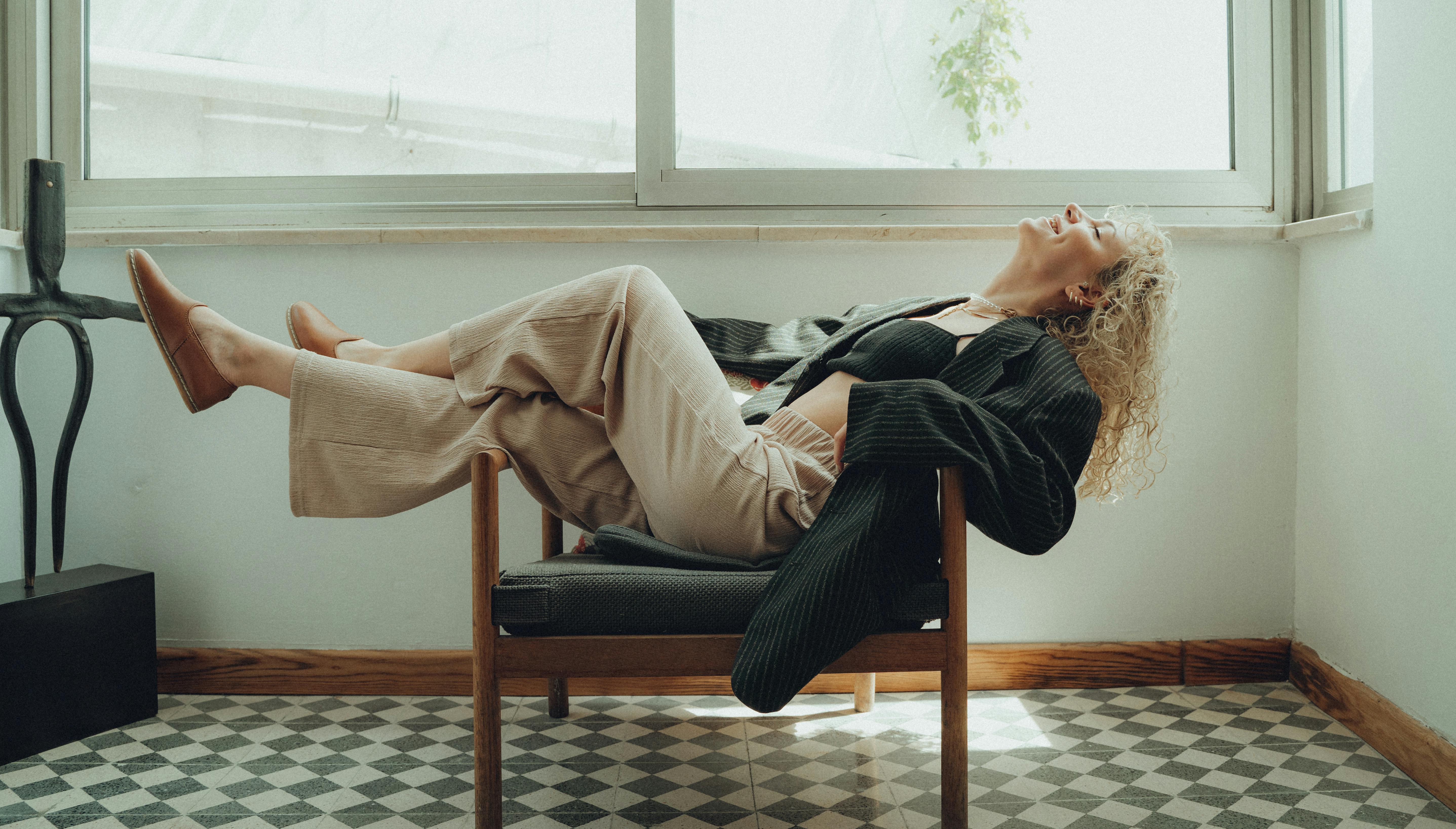 blonde woman lying down and posing on armchair