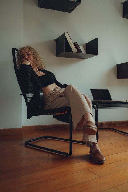 Fashionable woman sitting in a modern chair, embodying relaxed style in a chic room.