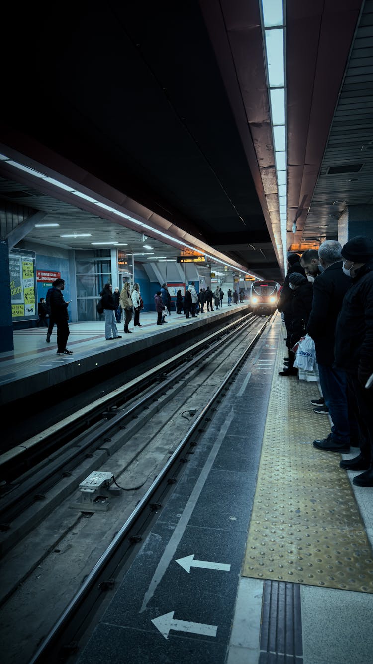 People Waiting On A Platform For The Train Aproaching, At Evening