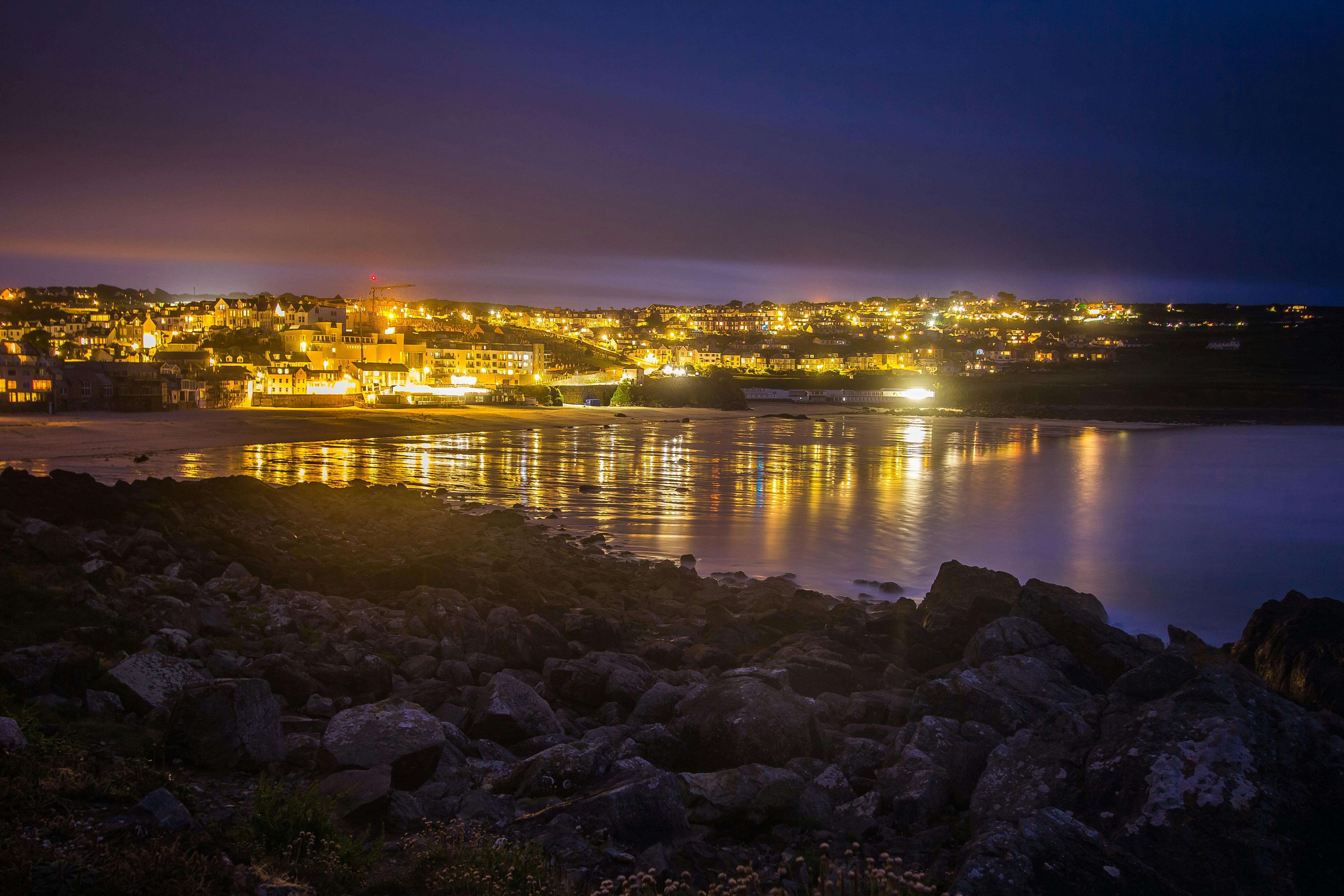 lighted city in distance near body of water