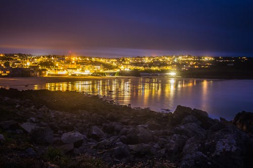 Lighted City in Distance Near Body of Water