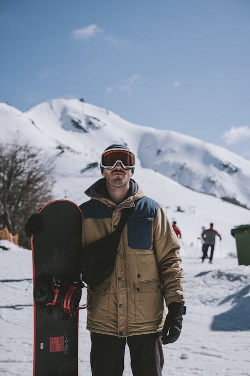 Man Wearing Goggles with a Snowboard on a Slope 