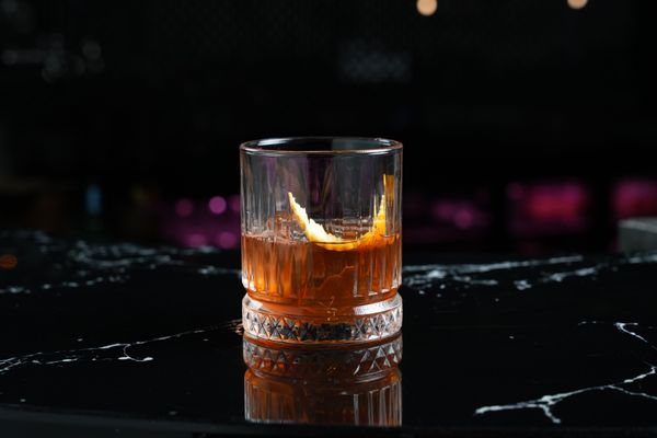 Cocktail glass with a citrus garnish on a dark marble bar. Photo by Dextar Studio on Pexels.