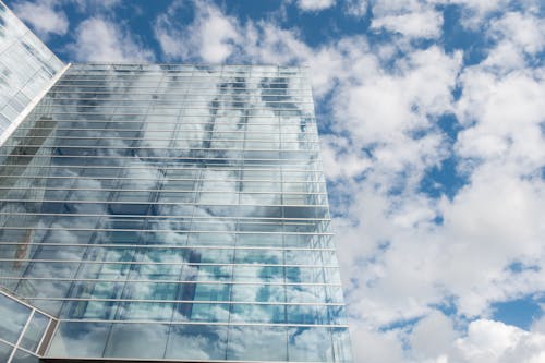 Free Bottom View of Clear Glass Building Under Blue Cloudy Sky during Day Time Stock Photo